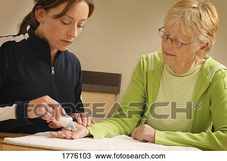 Stock Image - Salve being put on woman's hand. Fotosearch