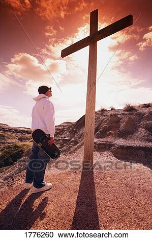 Skateboarder standing before a cross View Large Photo Image Stock Image - Skateboarder standing before a cross. Fotosearch