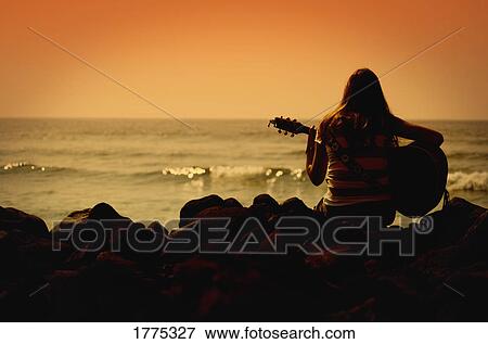 Woman playing the guitar and looking out to sea View Large Photo Image Stock Photo - Woman playing the guitar and looking out to sea. Fotosearch