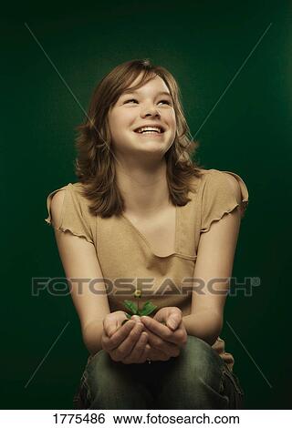 Young girl holding a young plant View Large Photo Image Stock Photograph - Young girl holding a young plant. Fotosearch