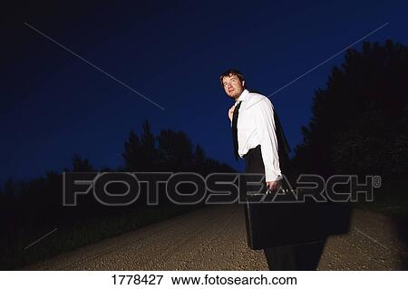 Stock Photo - A business person on a gravel road. Fotosearch