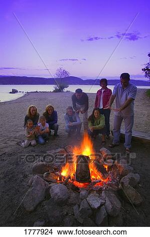 A group of people around a fire on the beach View Large Photo Image Picture - A group of people around a fire on the beach. Fotosearch