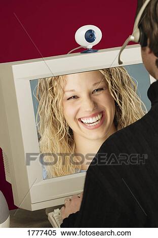 Stock Photography - A man working at a computer, using a webcam. Fotosearch