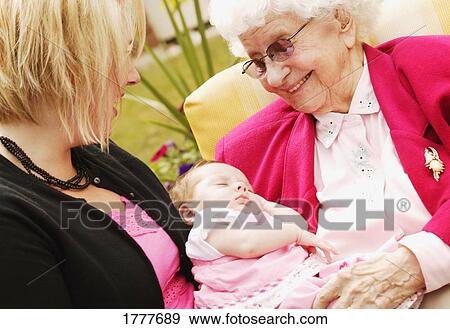 A senior woman holding a baby with a young woman beside her View Large Photo Image Stock Photo - A senior woman holding a baby with a young woman beside her. Fotosearch