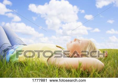A teenage girl lying in the grass on a summer day View Large Photo Image Stock Image - A teenage girl lying in the grass on a summer day. Fotosearch