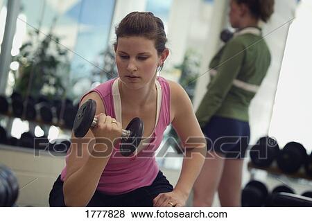 Stock Photo - A woman using a dumbbell. Fotosearch