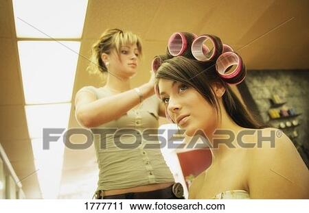 Stock Image - A young woman having her hair styled. Fotosearch