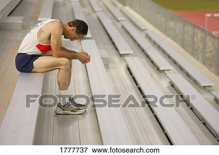 An athlete resting on a bench in the stands of a stadium View Large Photo Image Stock Photo - An athlete resting on a bench in the stands of a stadium. Fotosearch