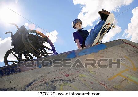 Brave skateboarder sits on the edge View Large Photo Image Stock Photo - Brave skateboarder sits on the edge. Fotosearch