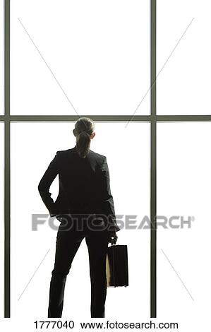 Stock Image - Business woman looking out a window. Fotosearch