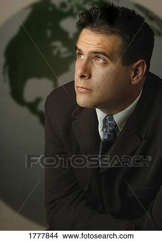 Picture - Businessman thinking in front of a globe. Fotosearch