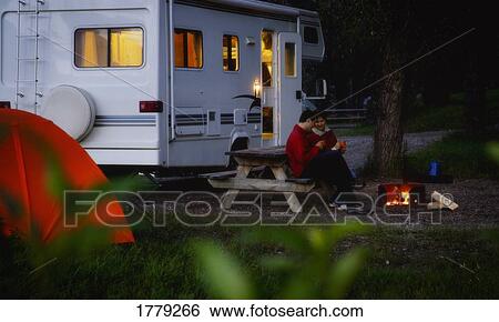 Stock Photograph - Couple sitting by campfire. Fotosearch