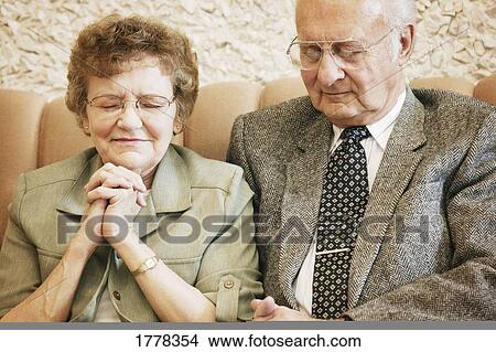 Picture - Elderly couple praying. Fotosearch