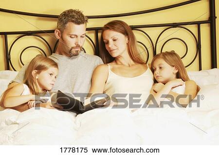 Family in bed reading bible View Large Photo Image Stock Photography - Family in bed reading bible. Fotosearch