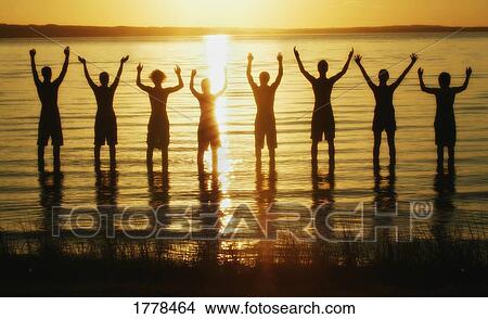 Picture - Line of men in water with arms raised. Fotosearch