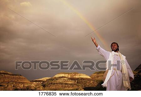 Stock Photography - Man with outstretched arm, rainbow in background. Fotosearch