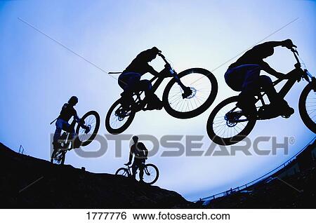 Stock Photograph - Stunt cyclists in silhouette. Fotosearch