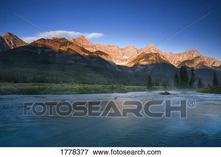 Stock Photo - Sunrise and early morning mist on river Elk Lakes. Fotosearch