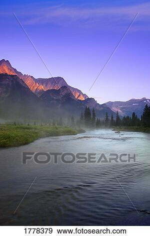 Stock Photo - Sunrise and early morning mist on river Elk Lakes Provincial Park. Fotosearch