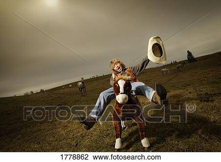 Stock Image - Teenage cowboy on stuffed horse. Fotosearch