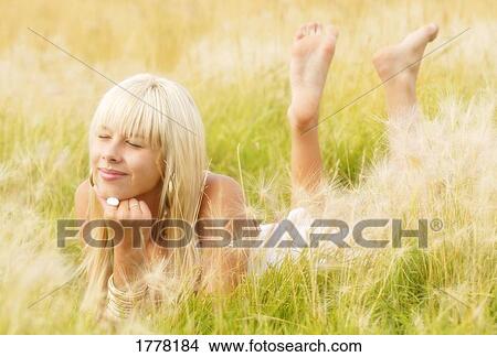 Picture - Teenager girl lying in grass wishing. Fotosearch
