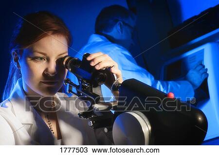 Stock Image - Woman looking into microscope. Fotosearch