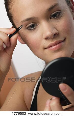 Woman using tweezers on her eyebrows View Large Photo Image Stock Image - Woman using tweezers on her eyebrows. Fotosearch