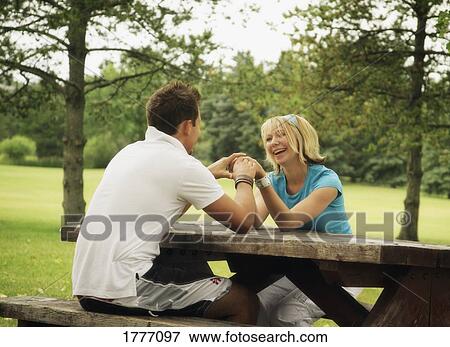 Young couple sitting at a picnic table View Large Photo Image Stock Photo - Young couple sitting at a picnic table. Fotosearch