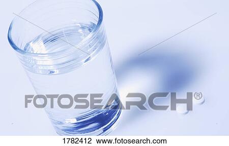 Stock Image - A cup of water with pills. Fotosearch