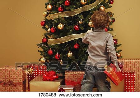 Stock Photo - Child with presents and Christmas tree. Fotosearch