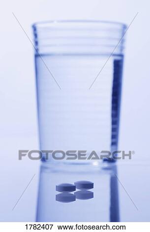 Stock Photo - Closeup of pills with water. Fotosearch