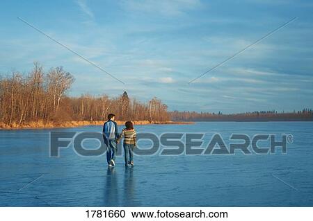Couple walking on a frozen lake View Large Photo Image Stock Image - Couple walking on a frozen lake. Fotosearch