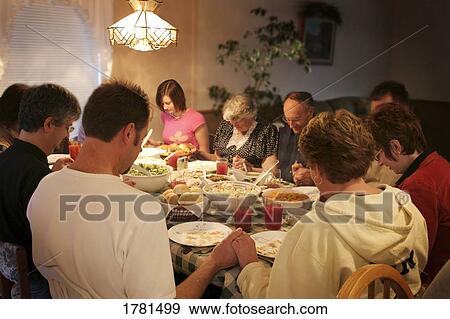 Stock Photo - Family praying over meal. Fotosearch