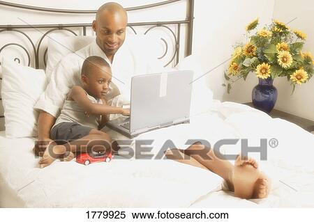 Stock Photography - Father and son hanging out in bed. Fotosearch