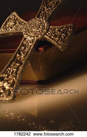 Stock Image - Gold cross resting on closed bible. Fotosearch