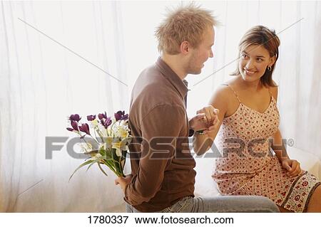 Stock Photo - Man hides bouquet behind his back. Fotosearch