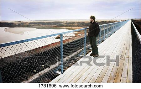 Stock Photograph - Man standing on a boardwalk. Fotosearch