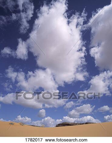 Sand dunes with clouds in the sky View Large Photo Image Stock Photo - Sand dunes with clouds in the sky. Fotosearch