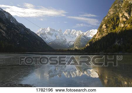 Stock Photograph - Snow covered mountain range reflected in alpine lake. Fotosearch