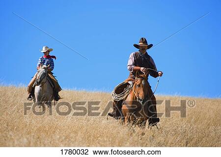 Stock Image - Two cowboys in a field. Fotosearch