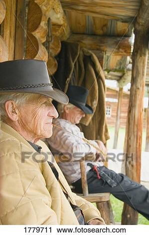 Stock Image - Two men relaxing on veranda. Fotosearch