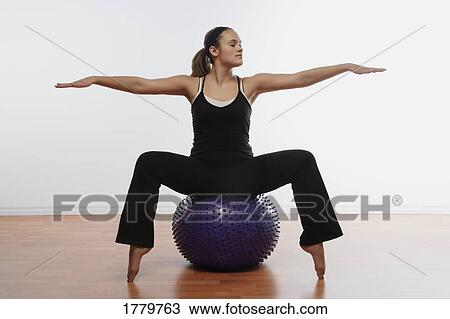 Stock Image - Woman sitting on exercise ball. Fotosearch