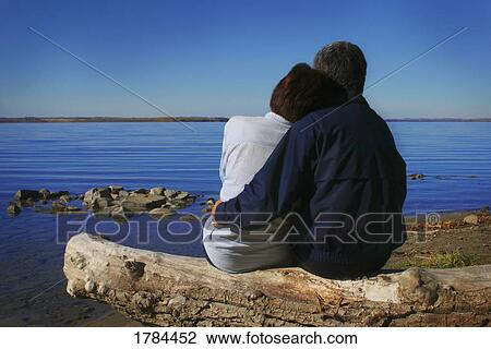 Stock Image - A couple cuddling by a beautiful lake. Fotosearch