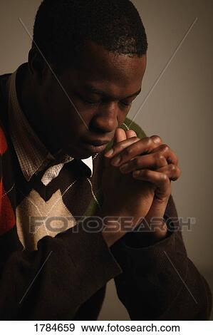 Stock Photo - A young adult in prayer or reflection. Fotosearch