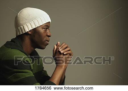 Stock Photograph - A young adult reflecting on a thought or in prayer.. Fotosearch