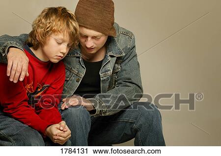 Stock Image - Boy and man praying together. Fotosearch