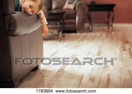 Picture - Child laying around on sofa. Fotosearch