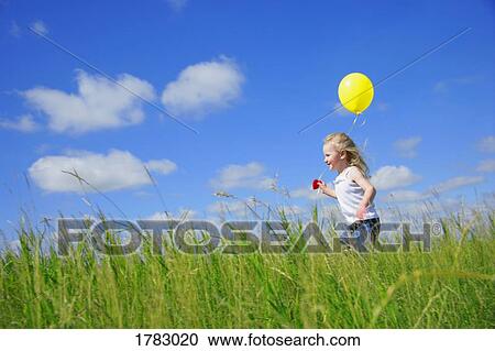 Stock Image - Child running with a balloon. Fotosearch
