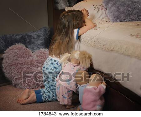 Stock Image - Child spends time in prayer with dolls. Fotosearch