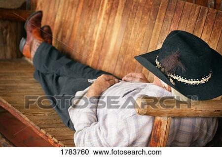 Cowboy resting on a bench View Large Photo Image Stock Image - Cowboy resting on a bench. Fotosearch